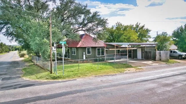 a backyard of a house with table and chairs under an umbrella