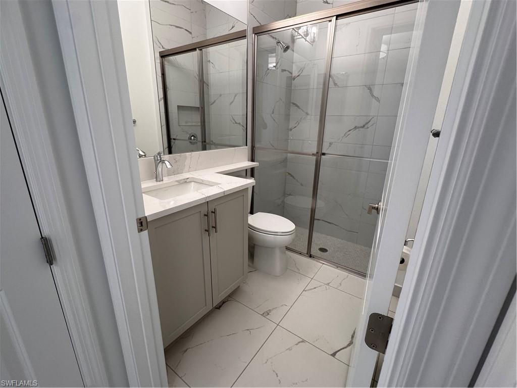2864 Bloomfield Way Naples, FL 34112 - Photo 16 of 40 a bathroom with a granite countertop sink toilet and shower