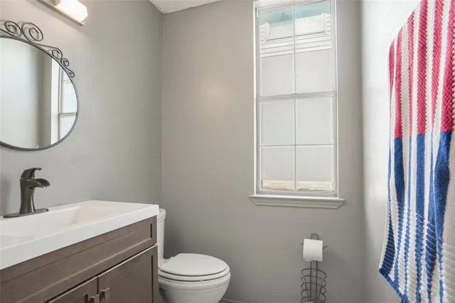 a bathroom with a toilet a sink a vanity and mirror