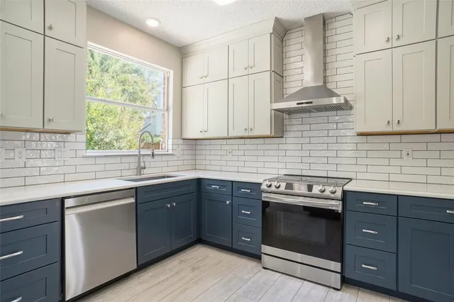 a kitchen with stainless steel appliances granite countertop a sink a stove and cabinets