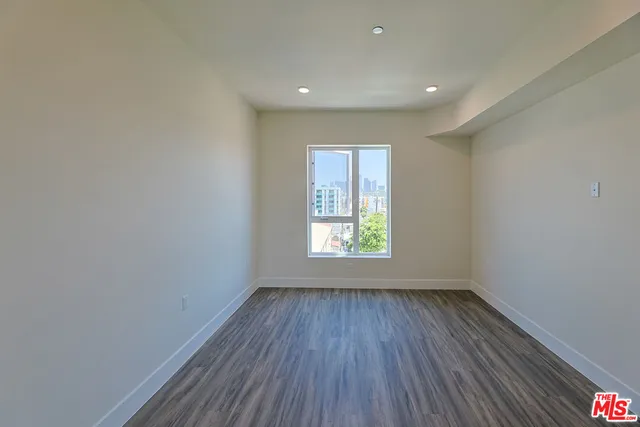 a view of an empty room with wooden floor and window