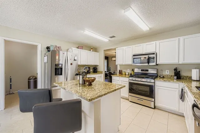 a kitchen with stainless steel appliances granite countertop a sink dishwasher stove refrigerator and cabinets