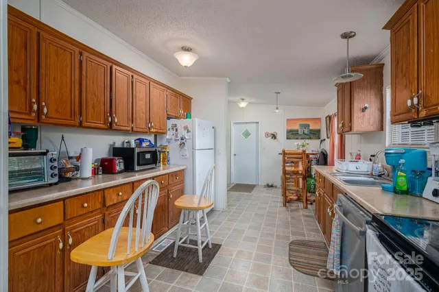 a kitchen with stainless steel appliances kitchen island granite countertop a table chairs in it and a window