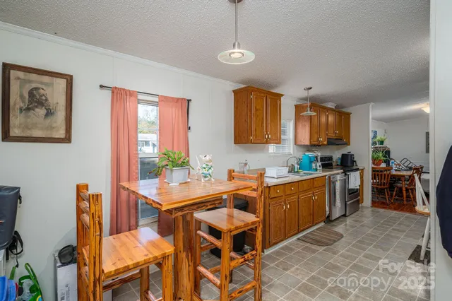 a room with stainless steel appliances kitchen island granite countertop a table chairs sink and cabinets