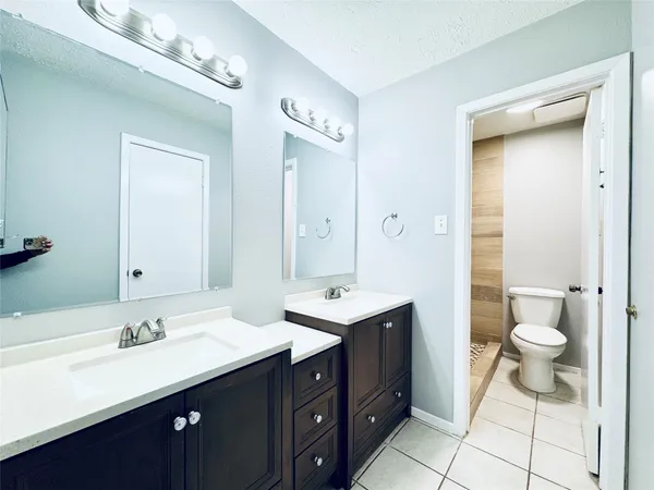 a bathroom with a double vanity sink a toilet and a mirror