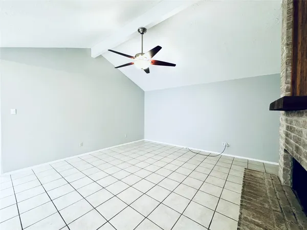 a view of an empty room and chandelier fan
