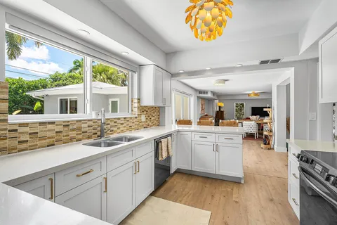 a large white kitchen with stainless steel appliances granite countertop a stove and a sink