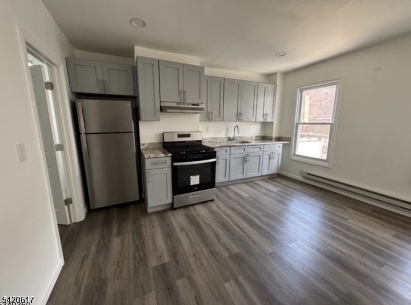 76 Market Street, Unit 1 Paterson, NJ 07505 - Photo 1 of 1 a kitchen with a refrigerator a sink and wooden floor