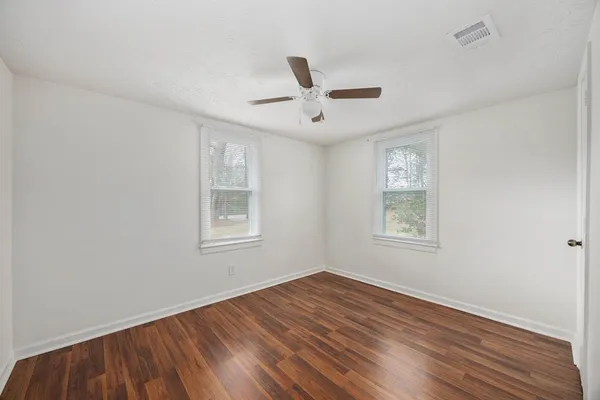 a view of an empty room with a window and wooden floor