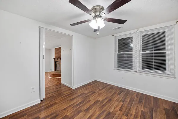 a view of an empty room with wooden floor and a window