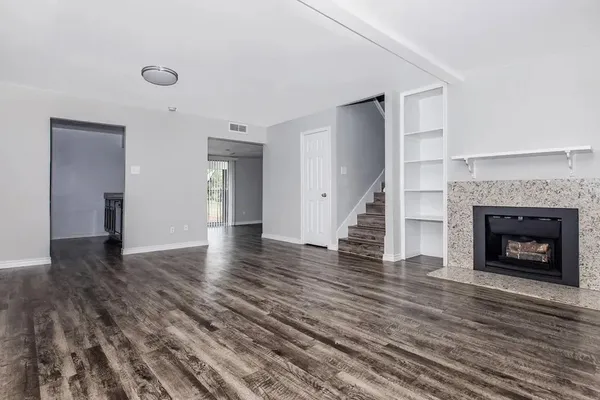 a view of a livingroom with wooden floor and a fireplace