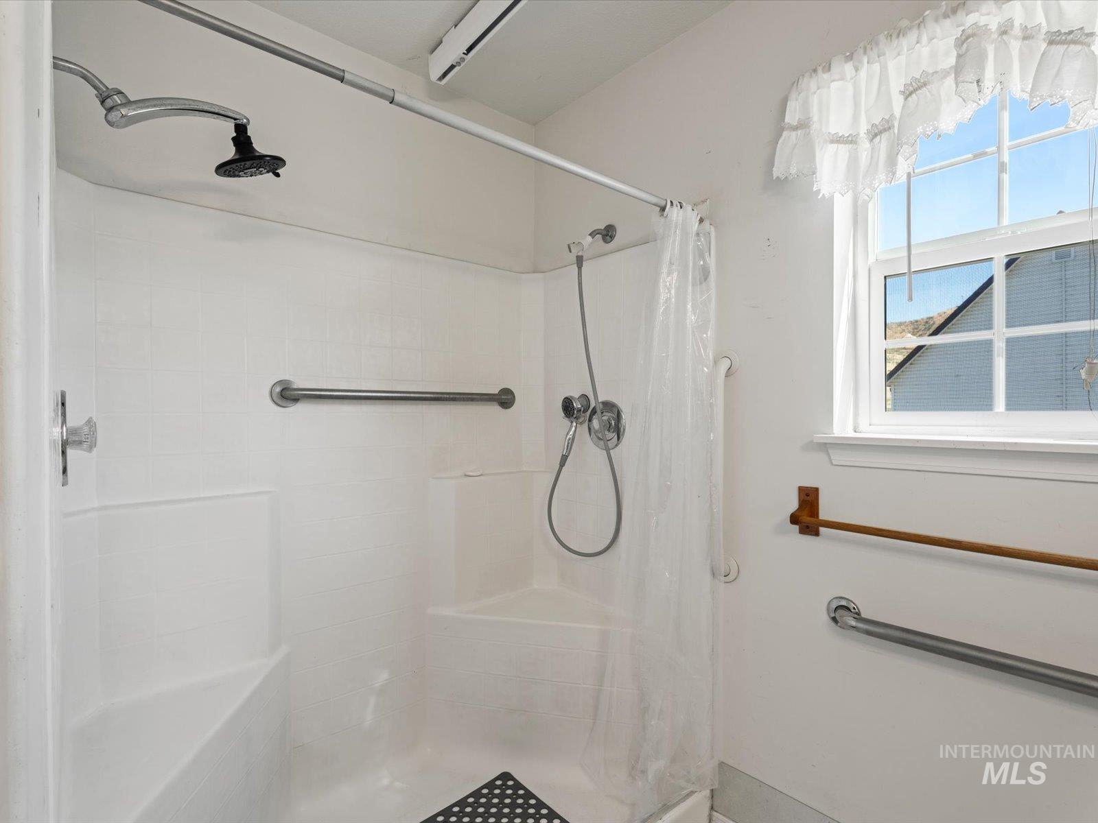 3540 Wills Road Emmett, ID 83617 - Photo 19 of 36 Shower enclosure featuring a built-in seat, handheld shower fixture, rain showerhead, and grab bars