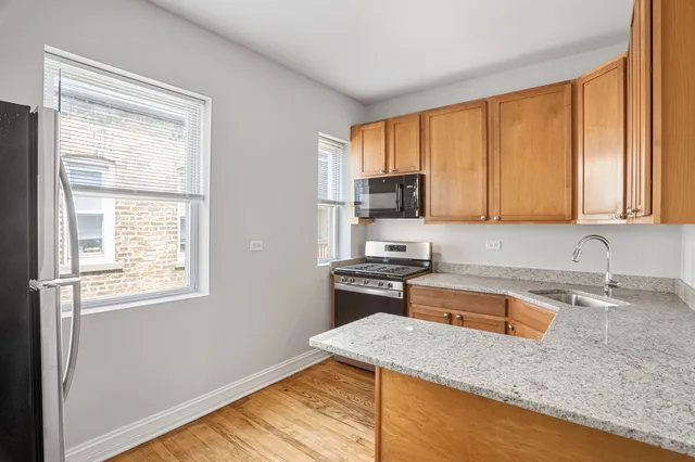 a kitchen with stainless steel appliances granite countertop wooden cabinets a stove a sink and dishwasher with wooden floor