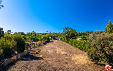 an aerial view of residential houses with outdoor space and trees