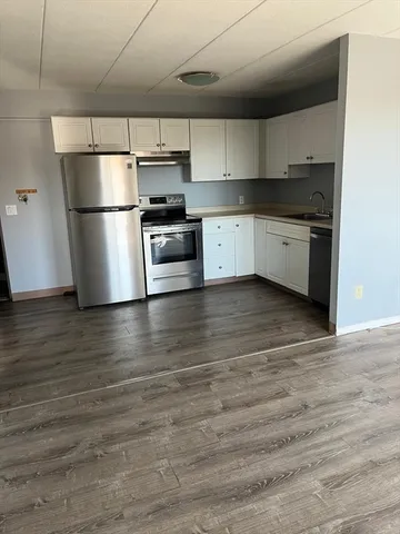 a kitchen with granite countertop a refrigerator and a stove top oven