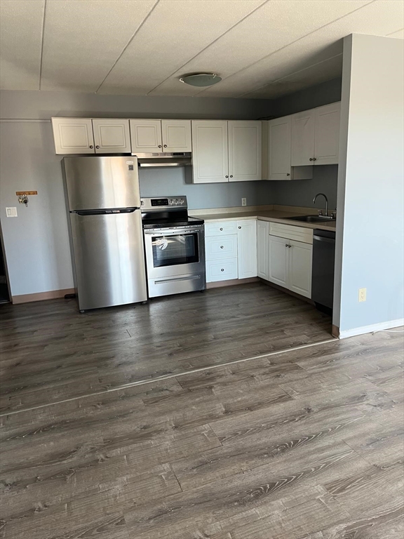 a kitchen with granite countertop a refrigerator and a stove top oven