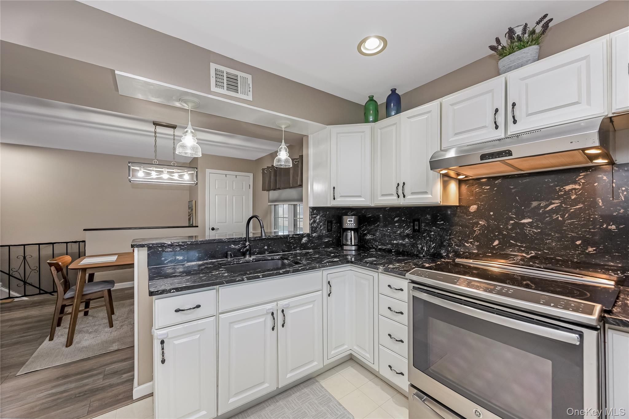 140 Mariners Way Copiague, NY 11726 - Photo 3 of 26 a kitchen with granite countertop white cabinets and white appliances