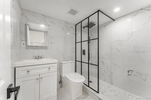 a bathroom with a toilet sink vanity granite and shower