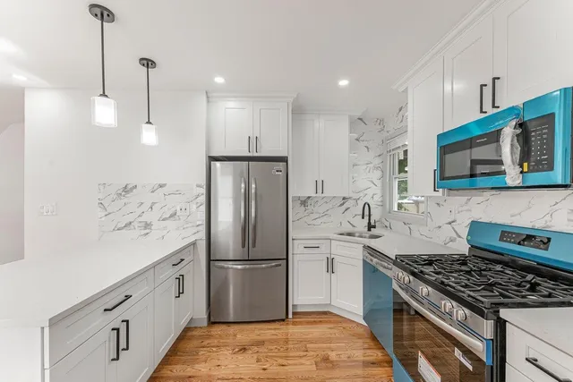 a kitchen with stainless steel appliances kitchen island granite countertop a refrigerator a stove and a sink with wooden floor