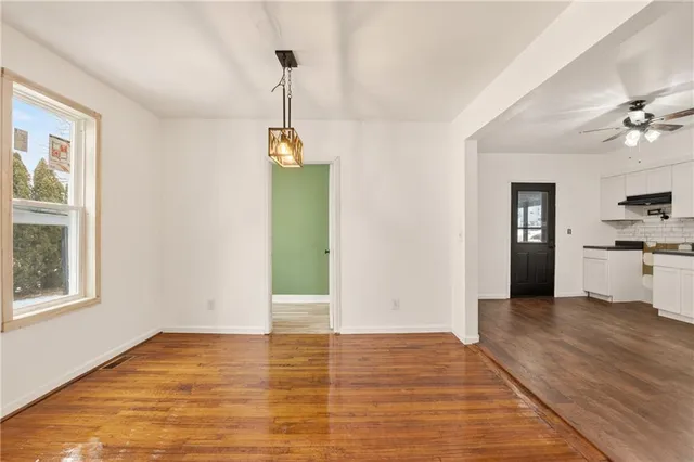 a view of an empty room with window and wooden floor