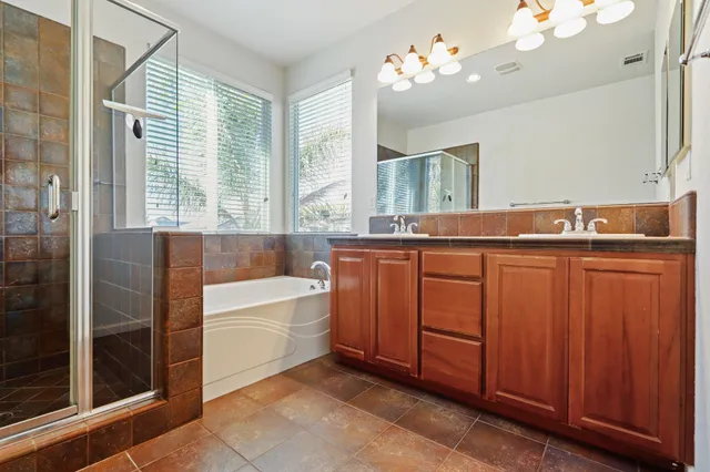 a spacious bathroom with a tub a double vanity sink a window and a mirror