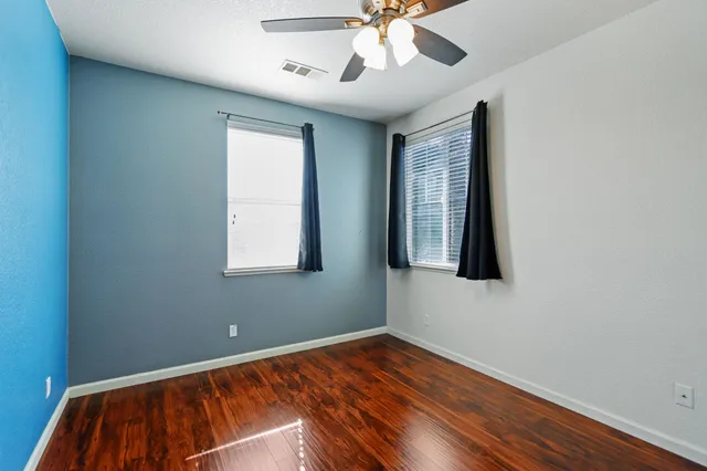 a view of an empty room with window and wooden floor