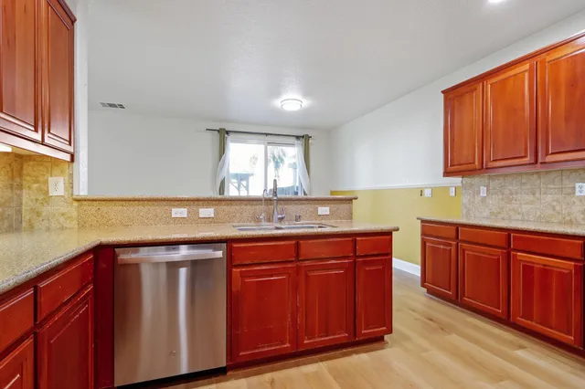 a kitchen with stainless steel appliances granite countertop wooden cabinets and a sink