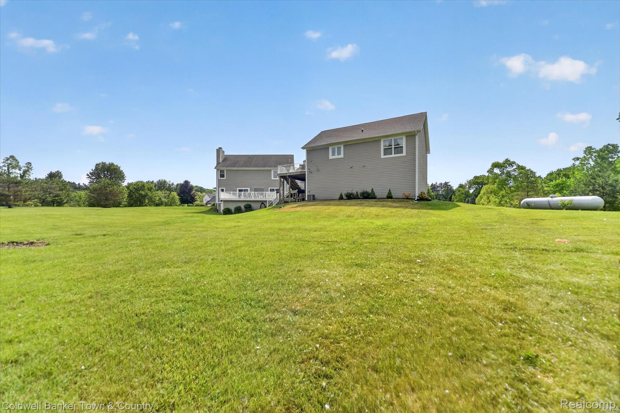 918 Gray Fox Court Howell, MI 48843 - Photo 65 of 84 Expansive green lawn surrounding a two-story residence with a light gray siding exterior, white trim windows, and a dark shingled roof