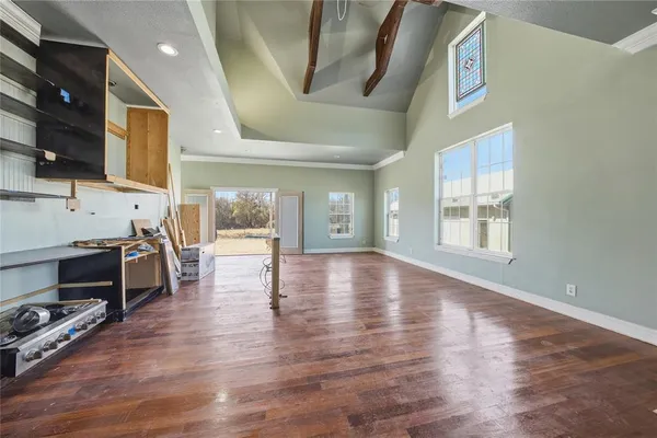 a view of an empty room with window and wooden floor