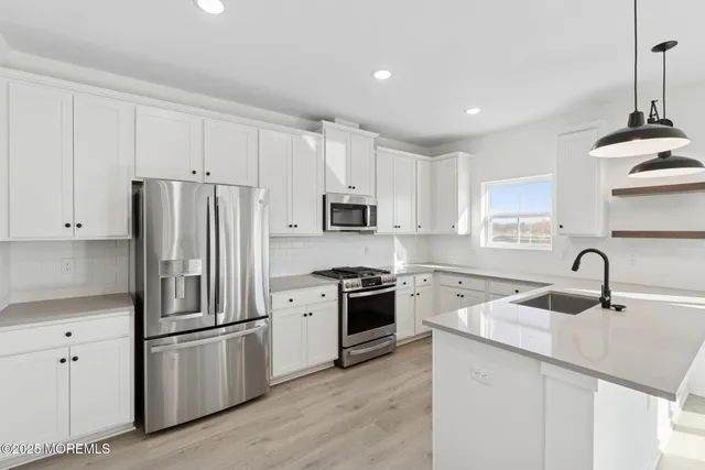 a kitchen with refrigerator a sink and white cabinets