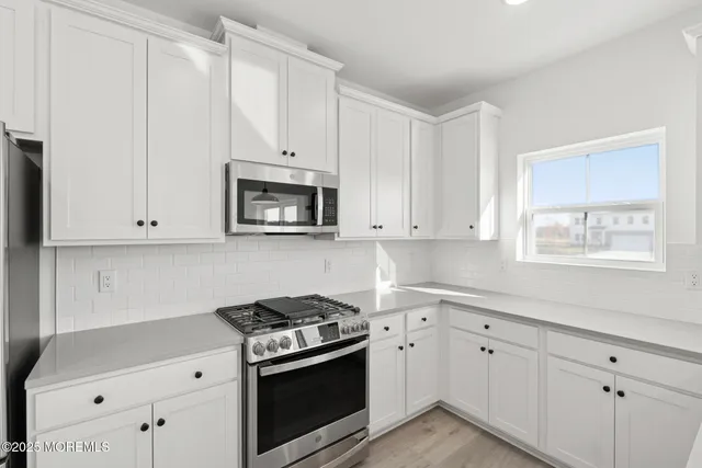 a kitchen with white cabinets and appliances