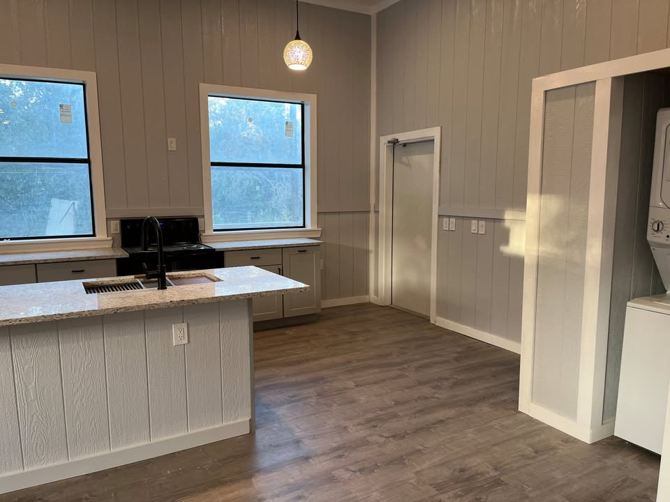 3505 Lone Man Mountain Road, Unit A Wimberley, TX 78676 - Photo 5 of 11 A well-lit kitchen space features durable wood-look flooring and a functional island with a built-in sink.