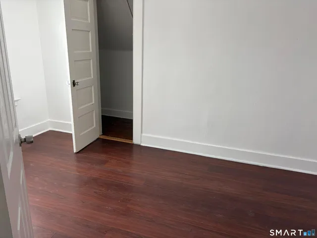 a view of an empty room with wooden floor and closet