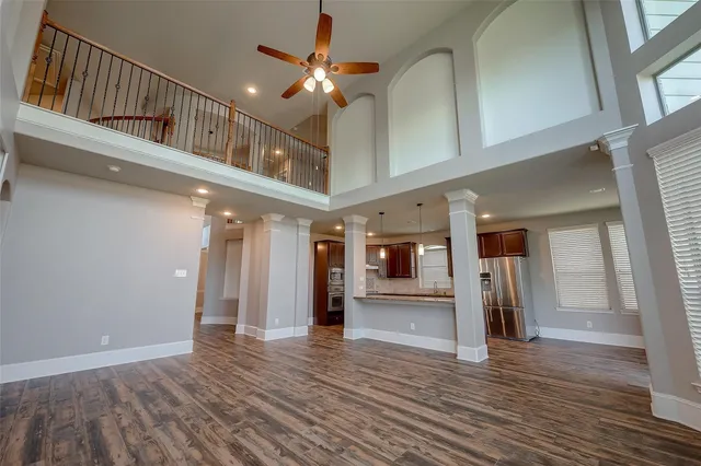 a view of a hallway with wooden floor and a kitchen