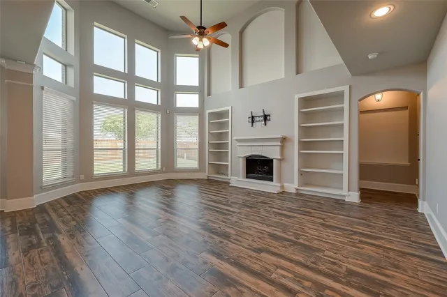 a view of an empty room with wooden floor fireplace and a window