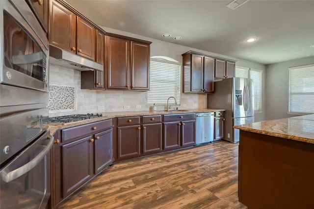 a kitchen with stainless steel appliances granite countertop a sink stove and refrigerator