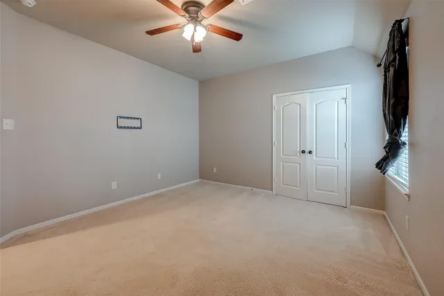 an empty room with chandelier fan and windows