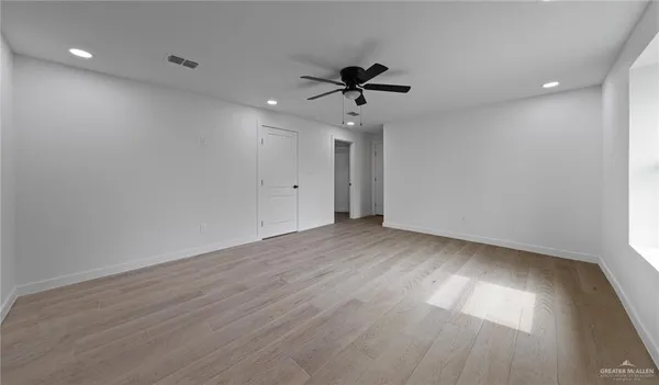 a view of empty room with wooden floor and fan