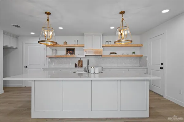 a kitchen with stainless steel appliances granite countertop a sink a stove and a wooden floors