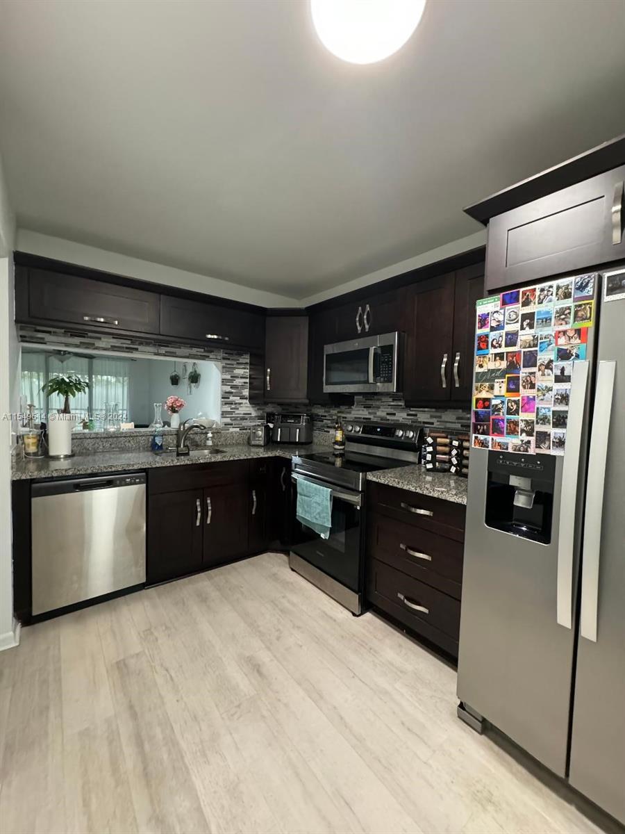 a kitchen with stainless steel appliances kitchen island granite countertop a refrigerator stove and sink