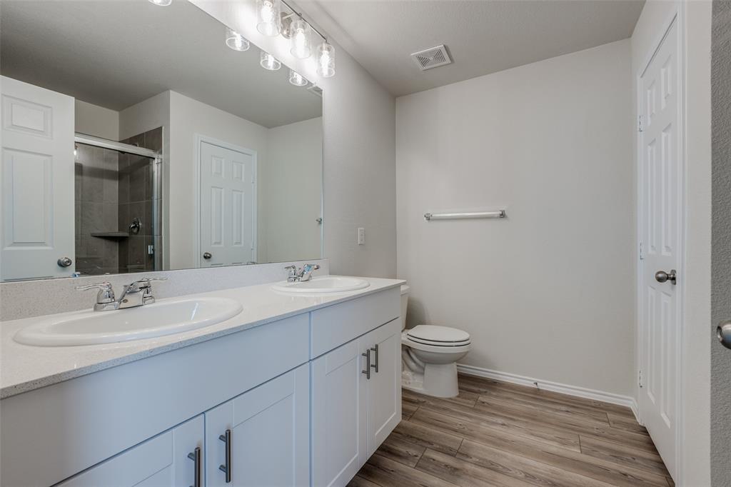 877 Table Rock Street Princeton, TX 75407 - Photo 14 of 25 a bathroom with a double vanity sink toilet and a mirror