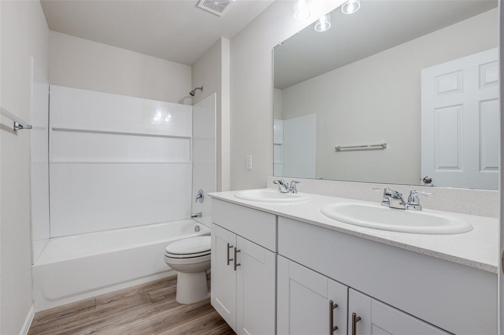 877 Table Rock Street Princeton, TX 75407 - Photo 20 of 25 a bathroom with a double vanity sink toilet and shower