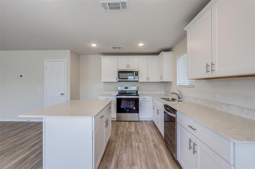 877 Table Rock Street Princeton, TX 75407 - Photo 5 of 25 a kitchen with granite countertop white cabinets and stainless steel appliances