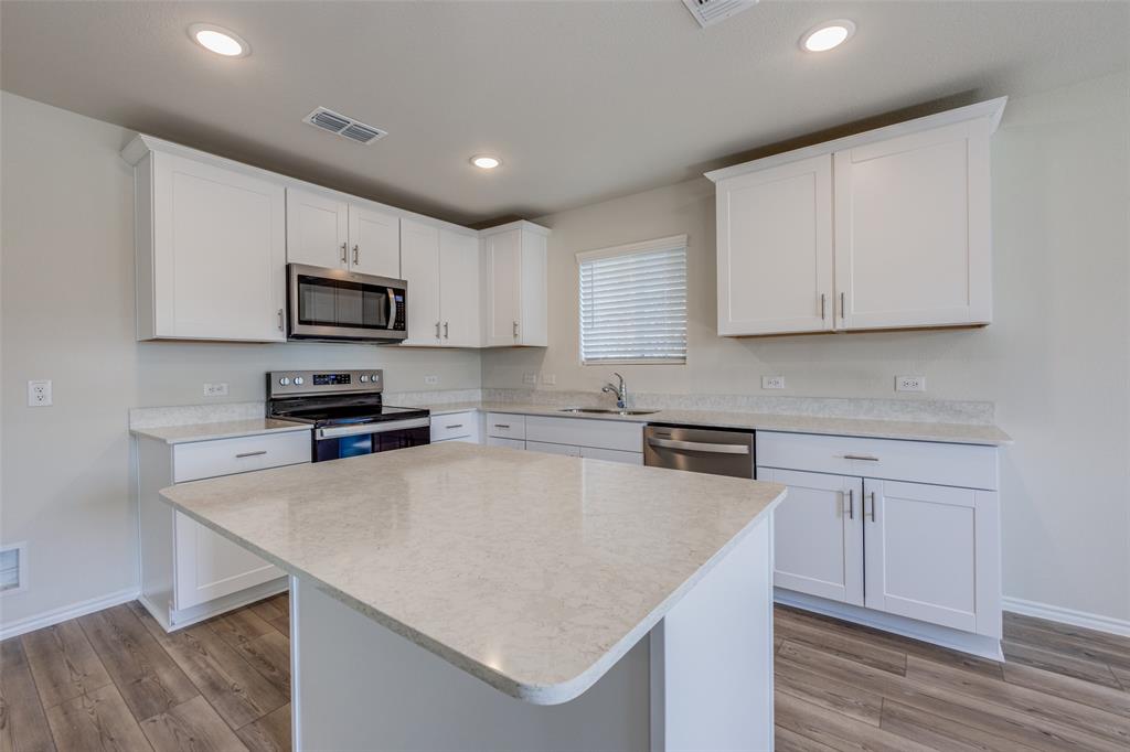 877 Table Rock Street Princeton, TX 75407 - Photo 6 of 25 a kitchen with kitchen island a stove microwave and sink