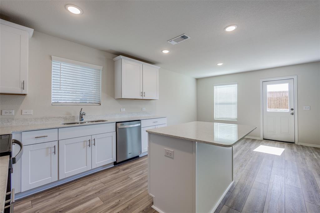 877 Table Rock Street Princeton, TX 75407 - Photo 10 of 25 a kitchen with granite countertop white cabinets and wooden floor