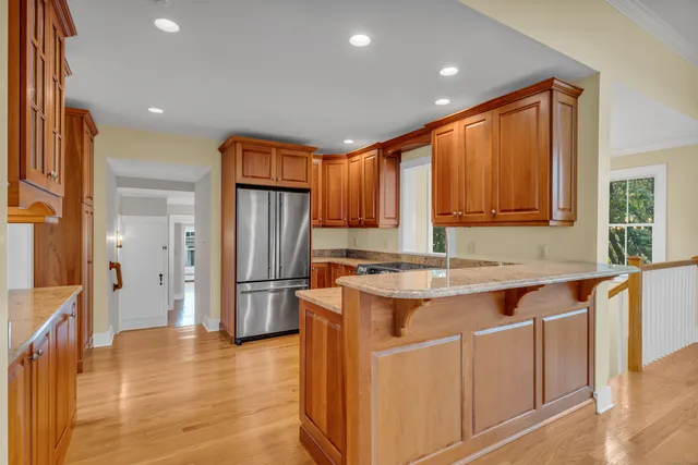 a kitchen with stainless steel appliances granite countertop a refrigerator a sink dishwasher a stove and a refrigerator with wooden floor