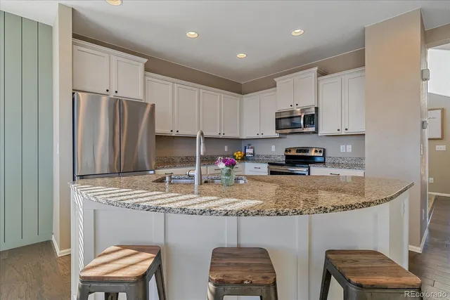 a kitchen with stainless steel appliances granite countertop a table chairs sink refrigerator and microwave