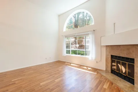 an empty room with wooden floor windows and fireplace
