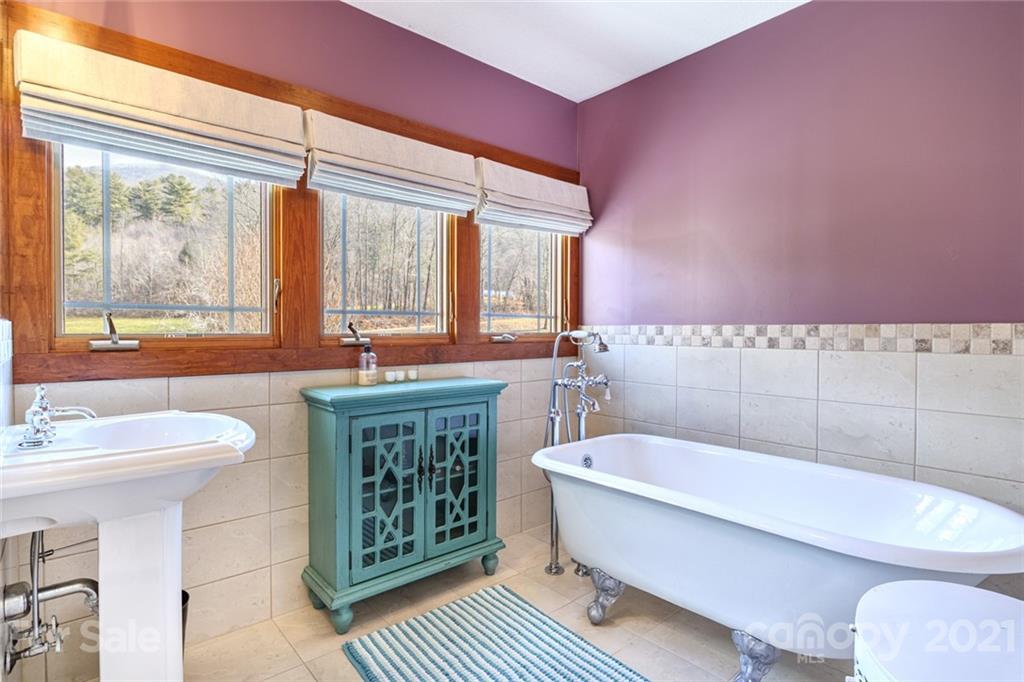 249 Ox Creek Road Weaverville, NC 28787 - Photo 17 of 32 a bathroom with a sink a toilet a mirror and bathtub