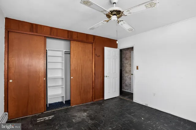 an empty room with closet and a ceiling fan